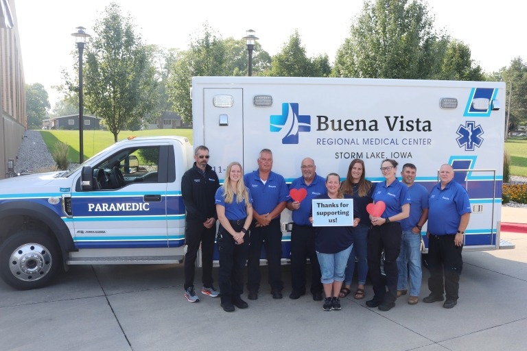 Team photo of BVRMC's ambulance department standing in front of the ambulance and holding a sign that says "Thanks for supporting us!"