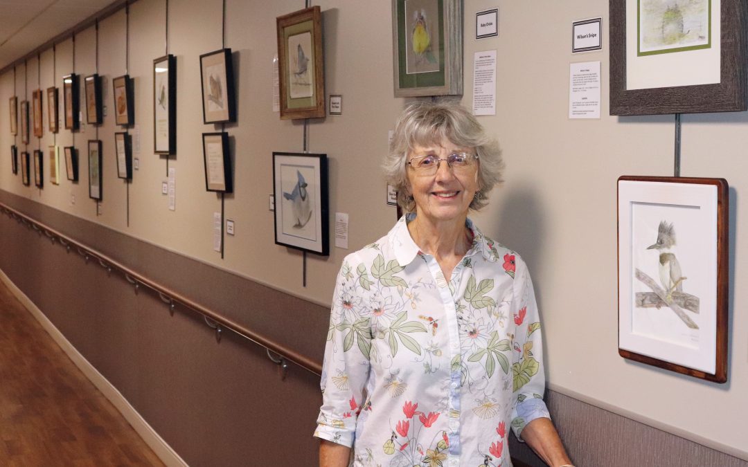 Artist standing by hanging artwork at BVRMC