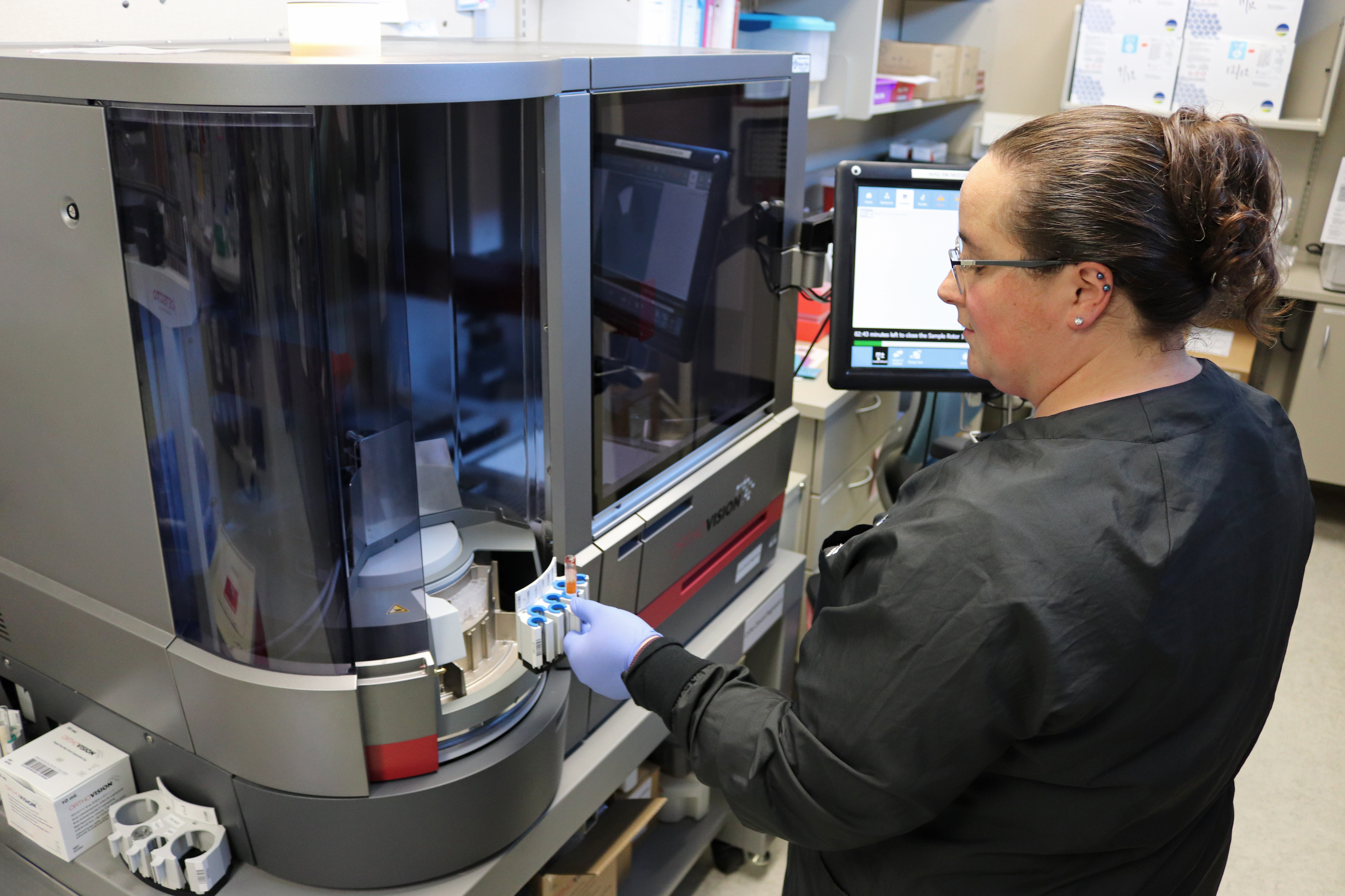 BVRMC lab employee standing in front of analyzer equipment in the lab